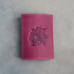 Fuchsia leather passport cover with a large floral initial N pressed into the front