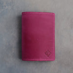 Fuchsia leather passport cover with a flower initial pressed into the bottom corner