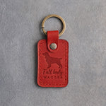 Poppy red leather keychain debossed with a springer spaniel and the words Full body WAGGER, on gray concrete