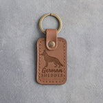 Caramel leather keychain debossed with a German shepherd silhouette and the words German SHEDDER, on gray concrete
