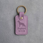 Lilac leather keychain debossed with a German Shepherd silhouette and the words Shepherd MOM, on gray concrete