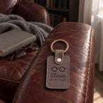 Gray Glasses ON MY HEAD keychain on a kitchen table beside a crossword and a pair of reading glasses