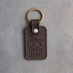 Dark espresso brown leather keychain debossed with a golden retriever silhouette and Golden DAD, on gray concrete