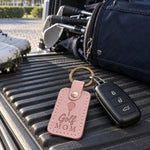 Pink Golf Mom keychain clipped to a white golf bag strap on a sunny practice green