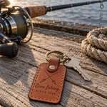 Arizona Gone fishing SINCE 2026 keychain in full-grain leather on sun-bleached dock boards beside a spinning rod in low evening sun