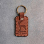 Warm tan leather keychain debossed with a whitetail buck above the words Gone HUNTING, on gray plaster