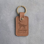 Caramel leather keychain debossed with a golden retriever and the words Good boy SINCE 2023, on gray concrete