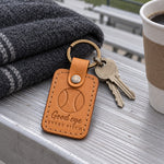 Good Eye keychain in warm brown leather on keys resting on aluminum bleachers in evening light