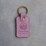 Lilac leather keychain debossed with an egg basket above the words Grandma's EGG MONEY, on gray concrete