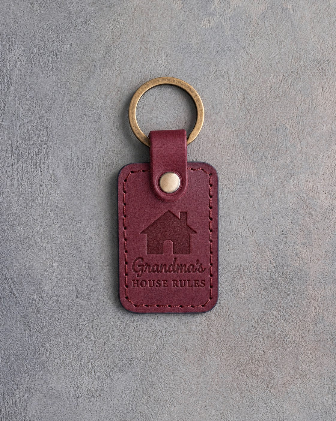 Sangria red leather keychain debossed with a gabled house above Grandma's and HOUSE RULES