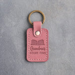 Parisian Blossom pink leather keychain debossed with an open book above Grandma's and STORY TIME, on gray concrete