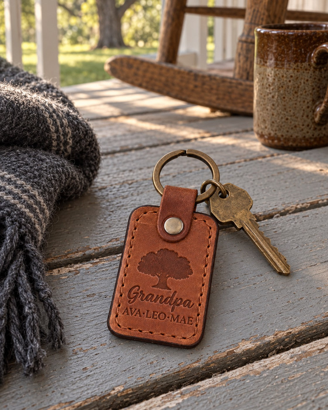 Tan Grandpa keychain with three grandchildren's names on car keys resting on a porch railing