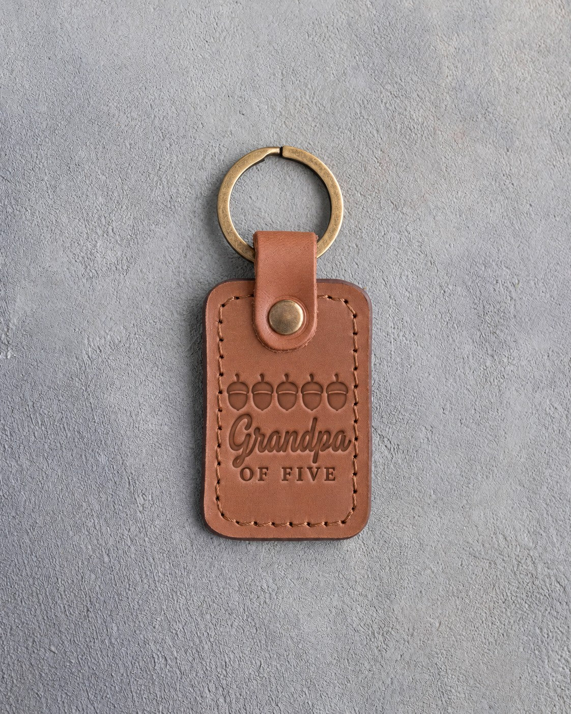 Caramel leather keychain debossed with a row of five acorns above Grandpa and OF FIVE