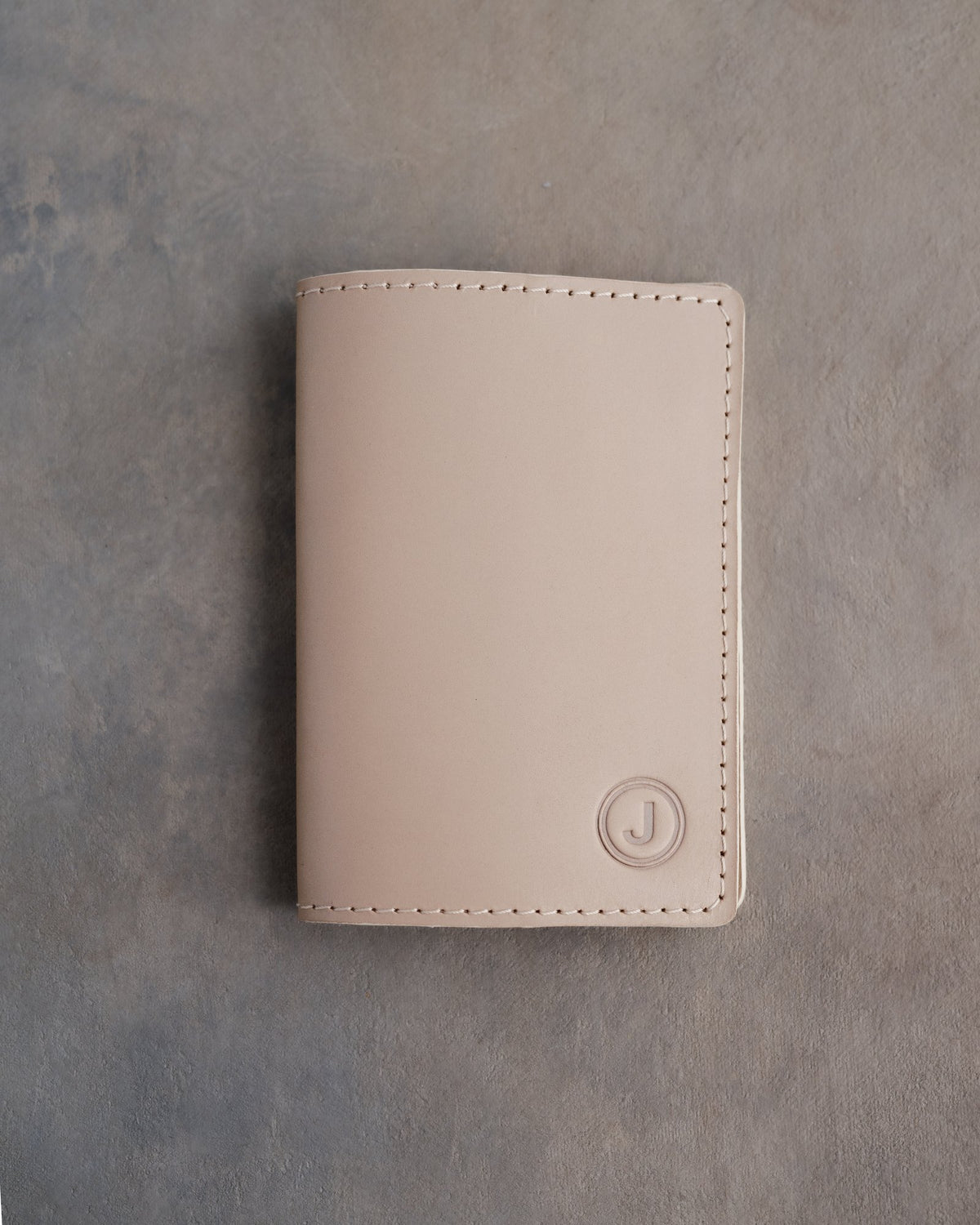 Gray Sand leather passport cover with the initial J in a circle pressed into the bottom corner