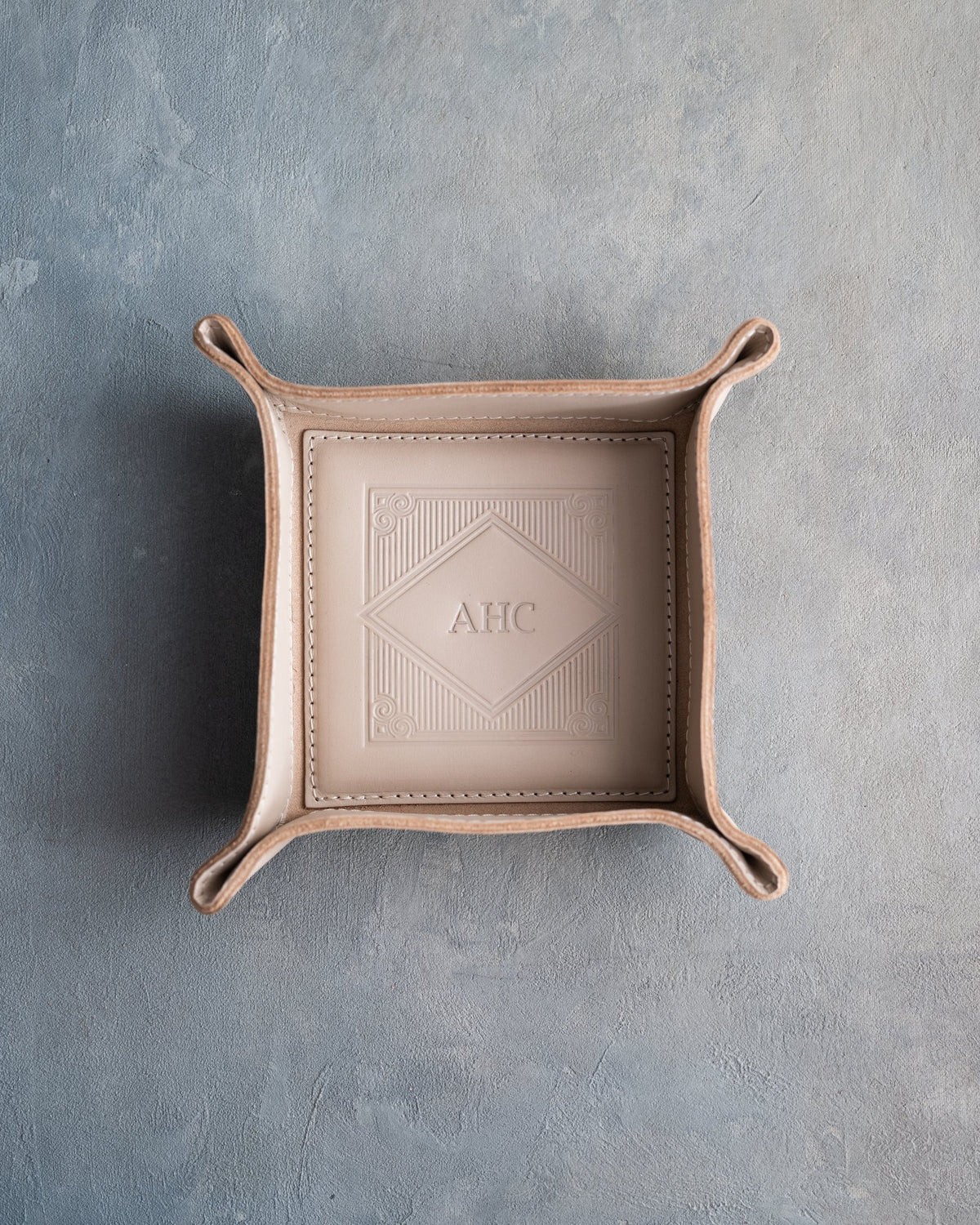 Gray Sand leather valet tray with snapped corners and the initials AHC pressed into the diamond frame, seen from above