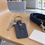 Navy Dane Dad keychain on a ring of keys tossed onto a wooden desk in lamplight