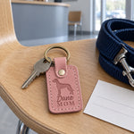 Pink Dane Mom keychain beside a handbag and sunglasses on a bright kitchen table