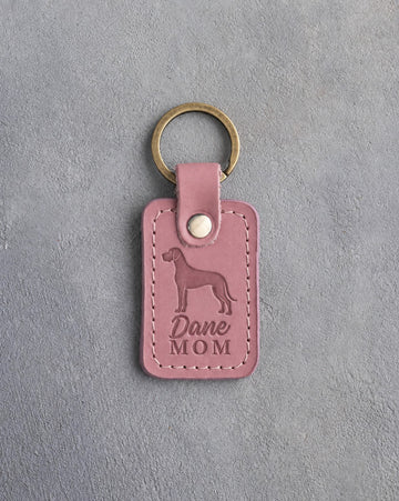 Parisian Blossom pink leather keychain with a debossed Great Dane and the words Dane MOM on gray concrete