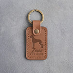 Caramel leather keychain debossed with a tall Great Dane above the name Zeus and THE DANE, on gray concrete