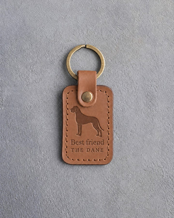 Caramel leather keychain debossed with a tall Great Dane above Best friend and THE DANE, on gray concrete