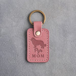 Parisian Blossom pink leather keychain with a debossed Great Pyrenees and the words Pyr MOM, on gray concrete