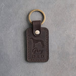 Dark espresso leather keychain debossed with a greyhound silhouette and Grey DAD, on gray concrete