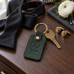 Tyler GROOMSMAN keychain in forest green leather on a walnut dresser beside a wristwatch and a pinned boutonniere