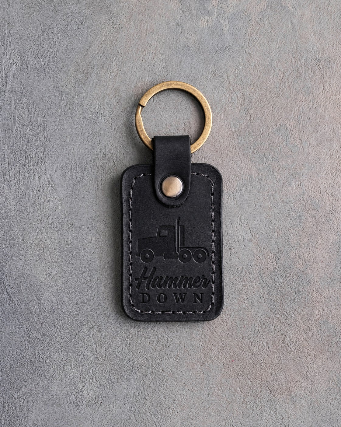 Black leather keychain debossed with a semi truck tractor above Hammer and DOWN