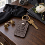 Has the RINGS keychain in gray leather on a walnut dresser next to cufflinks and a black bow tie