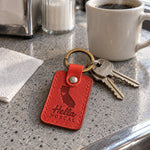 Red Hella NorCal keychain on car keys resting on a foggy hillside overlook above the bay