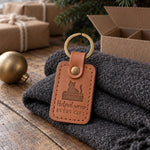 Caramel Helped Wrap Every Gift keychain on a table among rolls of kraft wrapping paper