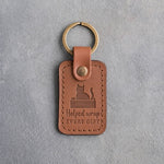 Caramel leather keychain debossed with a cat sitting in an open box above the words Helped wrap EVERY GIFT
