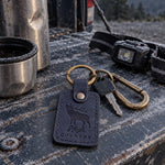 Navy High Country keychain clipped to a frame pack resting on a granite ledge above timberline