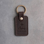 Dark espresso leather keychain debossed with a four-point star above Home and 44.76N 85.62W, on gray concrete