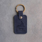 Blueberry navy leather keychain debossed with a cat on a windowsill above the words Home FOR CHRISTMAS