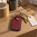 Wine red Home for Christmas keychain on a house key hanging from a stocking on a mantel with string lights