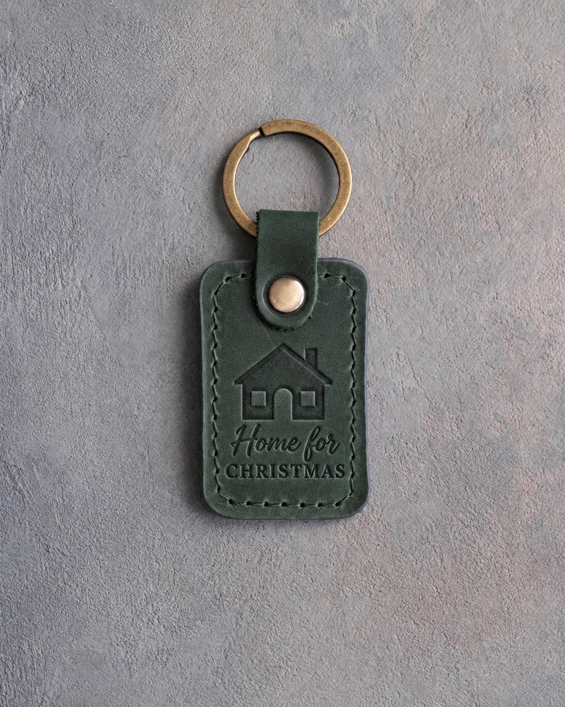 Forest green leather keychain debossed with a house with two lit windows above Home for and CHRISTMAS