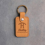 Indian Summer tan leather keychain debossed with a Swinging H ranch brand above the name Hadley and HOMESTEAD, on gray plaster
