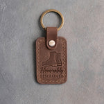 Sicilian brown leather keychain debossed with a pair of service boots above the words Honorably DISCHARGED, on gray concrete