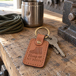 Caramel Hung up My Boots keychain on a house key hanging from a hook beside an empty pair of boots