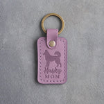 Lilac leather keychain debossed with a Siberian Husky silhouette and the words Husky MOM, on gray concrete