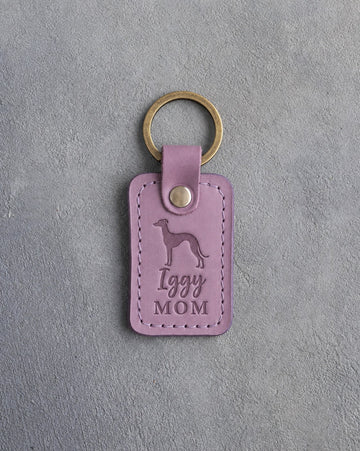 Lilac leather keychain debossed with an Italian Greyhound silhouette and the words Iggy MOM, on gray concrete