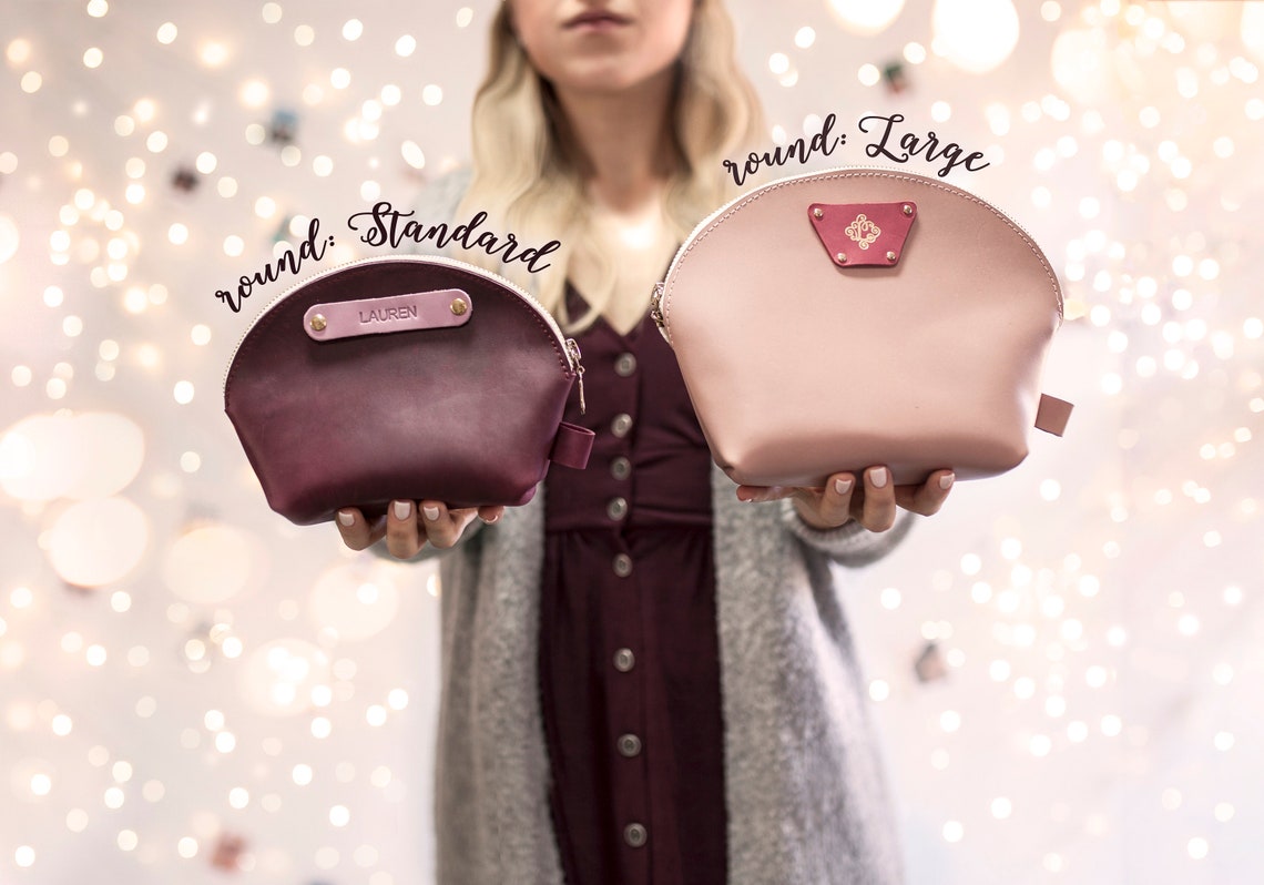 Round makeup bags in standard and large sizes held side by side in sangria and blush leather