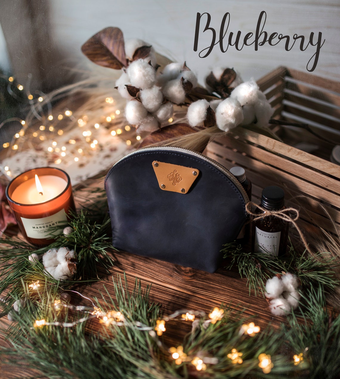 Blueberry navy round leather makeup bag with a leather name patch, cotton stems and a candle nearby