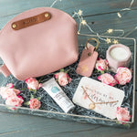 Blush round makeup bag with a name patch in a gift box surrounded by pink roses
