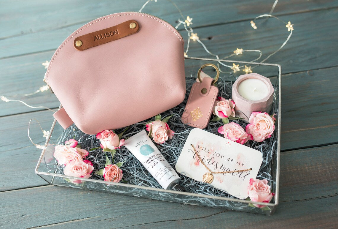 Blush round makeup bag with a name patch in a gift box surrounded by pink roses
