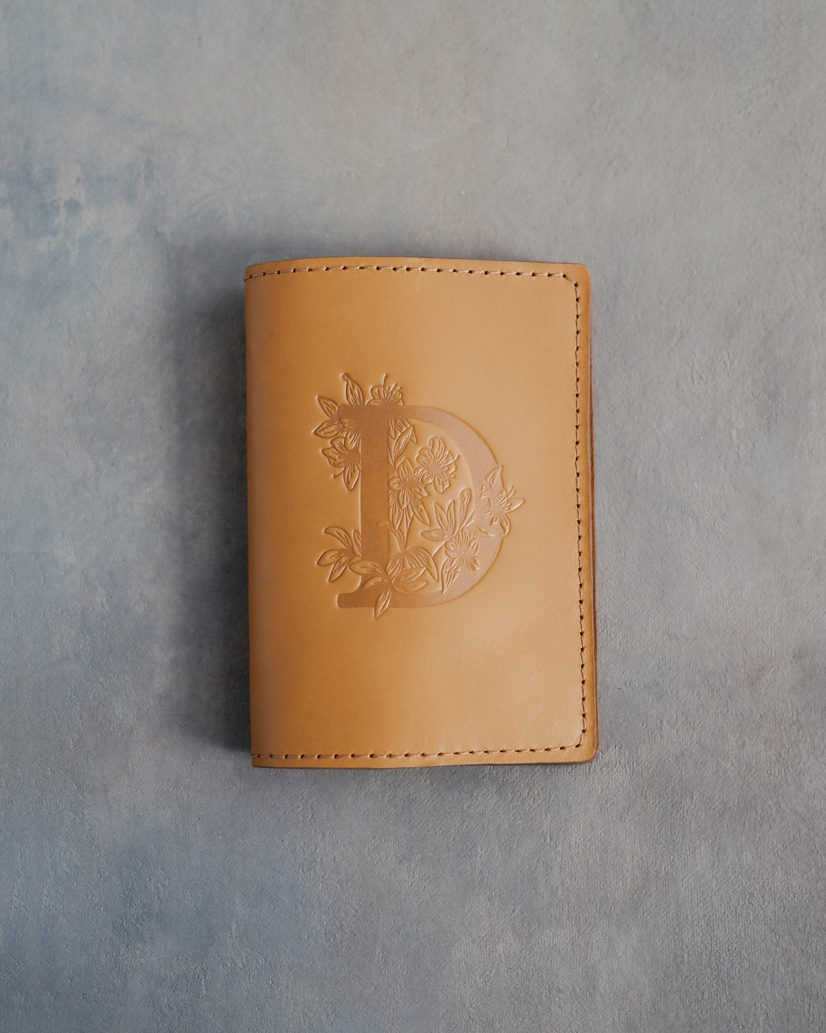 Indian Summer leather passport cover with a large floral initial D pressed into the front