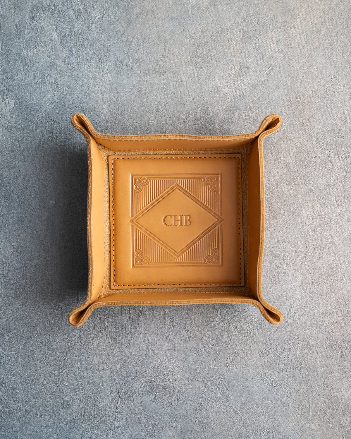 Indian Summer leather valet tray with snapped corners and the initials CHB pressed into the diamond frame, seen from above