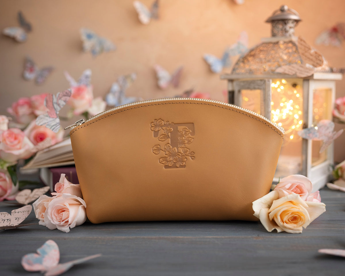 Indian summer initial makeup pouch with a floral monogram, staged among pale roses on a slate table