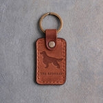 Arizona tan leather keychain debossed with an Irish Setter silhouette above THE REDHEAD, on gray concrete